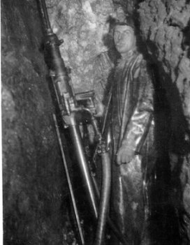 Andy Cruickshack with drill in slope. The white streak is the vein with gold in it, wpH372