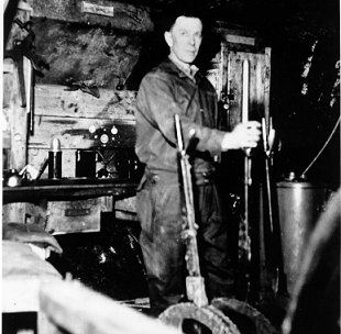  L. Boucher standing in front of some machinery, holding levers, wpH459